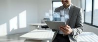 Professional businessman using digital tablet with holographic cloud computing interface in modern office environment for technology and data management solutions.