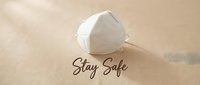 White N95 respirator mask on beige linen background with Stay Safe handwritten text, health protection concept for pandemic awareness.
