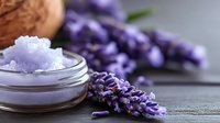 Aromatic lavender flowers with natural bath salt in glass jar on dark wooden surface, spa wellness composition for relaxation and skincare treatment.