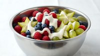 Fresh mixed fruit salad with berries grapes and cream in stainless steel bowl healthy breakfast dessert snack organic natural food nutrition.