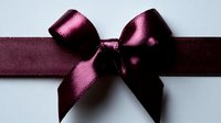 Elegant burgundy satin ribbon bow against white background, luxurious gift wrapping detail with rich deep wine color and silky sheen for festive occasions.