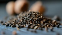 Aromatic black tea leaves scattered on dark wooden surface with brown eggs in soft focus background, macro food photography with selective focus.