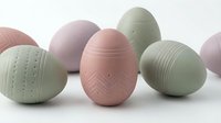 Pastel colored Easter eggs with geometric patterns in soft pink and sage green tones on white background for spring holiday decorations.