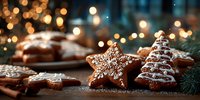 Festive gingerbread cookies with white icing decorations including star and Christmas tree shapes on wooden surface with warm bokeh lights background.