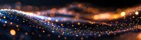 Glowing blue particles flow in curved wave formation against dark background with warm bokeh lights creating magical atmospheric effect.