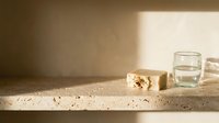 Organic soap bar with natural ingredients and glass of water on rustic stone shelf, minimalist wellness and spa product display for skincare and beauty branding.