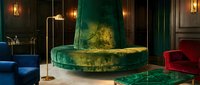 Luxurious emerald green velvet round sofa with golden accents in elegant dark interior with fireplace and ambient lighting for upscale home decor.