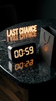 Digital alarm clock showing 00:59 on dark granite surface with glowing last chance neon text and shopping bag, urgency sale countdown concept.