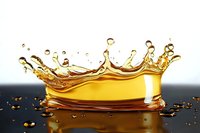 Golden liquid crown splash with droplets creating dynamic motion effect against dark background, captured in high-speed photography with reflection on surface.