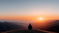 Person sitting alone on mountain peak watching golden sunrise over layered hills with birds flying in peaceful morning sky for meditation and wellness content.