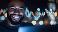 Cheerful African American male trader with glasses smiling at night, illuminated by stock market charts and city lights in background, showing success in trading.