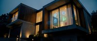 Modern luxury house exterior with warm interior lighting at dusk showcasing contemporary architecture and geometric design elements for real estate marketing.