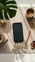 Smartphone with blank screen on linen desk mat, monstera leaf, coffee cup, dried flowers and pen, flat lay mockup for app or web design.