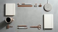 Minimalist workspace flat lay with white notebooks, coffee cup, copper accessories and stationery on gray background for branding and design projects.