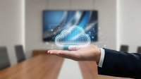 Business professional presenting cloud computing technology concept with glowing digital cloud icon floating above open palm in modern conference room.