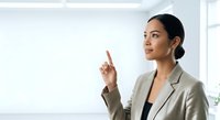 Young Southeast Asian woman in business attire presenting ideas on whiteboard in modern office environment, suitable for corporate training and professional development materials.