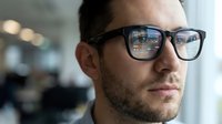 Professional businessman with eyeglasses in modern office environment reflecting technology and innovation in corporate workspace setting.
