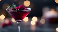 Vibrant red cocktail garnished with fresh raspberries and rosemary sprig in martini glass against blurred bokeh lights, creating elegant holiday atmosphere.