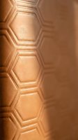 Metallic copper hexagonal embossed surface with geometric relief pattern and warm lighting, suitable for backgrounds, textures, and modern design projects.