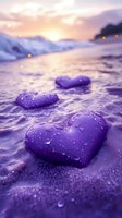 Purple heart-shaped stones with water droplets on beach sand at sunset creating romantic coastal scene for love and relationship concepts.