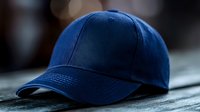 Navy blue baseball cap on dark textured surface with soft bokeh background lighting effect, classic sportswear accessory for casual style and branding mockup designs.