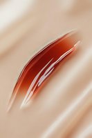 Luxurious red-brown cosmetic cream smear texture on beige background showing glossy, smooth consistency for beauty product advertising and packaging design.