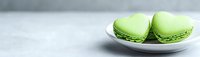 Green macarons on white plate against gray background, French pastry dessert for bakery menu, food photography, culinary arts, sweet treats.