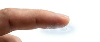Human finger touching clear transparent gel or cream substance on white background for skincare cosmetic product testing and application.