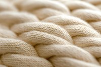 Soft cream colored knitted wool texture in macro view showing detailed yarn pattern and weave structure. Natural fiber material background for fashion and craft designs.