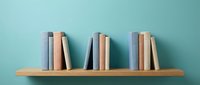 Wooden bookshelf with colorful books arranged in groups against turquoise wall background for home decor and reading concepts.