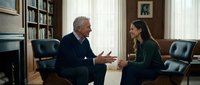 Professional therapy session with mature male therapist counseling young female client in elegant office setting with bookshelves and leather chairs.