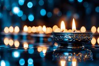 Ornate silver diya lamps with glowing flames against dark background with bokeh lights creating magical atmosphere for Diwali celebration or meditation.