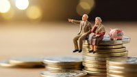 Miniature elderly couple sitting on stack of coins representing retirement planning and financial security for senior years.