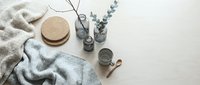 Cozy flat lay with knitted sweater, cork coasters, eucalyptus branches and candle on neutral background for home decor and lifestyle content.