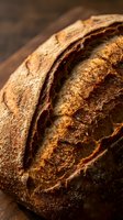 Freshly baked artisan sourdough bread with golden crust on rustic wooden board, close-up macro shot for food blogs and menus.