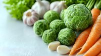 Fresh brussels sprouts, organic carrots and garlic cloves on light background. Healthy cooking ingredients for vegetarian and vegan meals. Natural food concept.