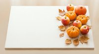 Autumn harvest composition with pumpkins, apples and golden leaves on white paper background for seasonal design projects and fall decorations.