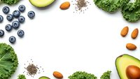 Healthy superfood frame with fresh blueberries, avocado, kale, almonds and chia seeds on white background with copy space for nutrition content.