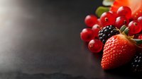 Fresh mixed berries including strawberry, blackberries and red currants on dark surface with copy space for healthy eating and nutrition concepts.