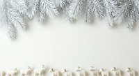 Frosted evergreen branches hang above scattered wooden gift boxes on white background, creating minimalist holiday composition for seasonal design projects.