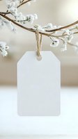 Blank white paper tag hanging on snowy winter branch with twine string, soft neutral background for adding text or design elements. Seasonal holiday mockup.