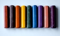 Colorful art pastel chalks arranged in row on white background. Vibrant spectrum of colors from red to purple shows artistic supplies for drawing and sketching.