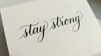 Stay strong handwritten calligraphy text on white paper card, isolated design element for motivational posters, greeting cards, and inspirational wall art projects.