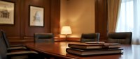 Elegant executive boardroom with polished wooden conference table, leather chairs, and warm lighting for corporate meetings and business presentations.