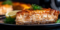 Flaky salmon fillet with golden-brown crust served on black plate with fresh dill and lemon garnish, close up view showing moist, tender texture and caramelized glaze.