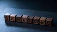 Wooden letter blocks spelling SERVICES on dark surface with dramatic lighting for business and professional concepts.