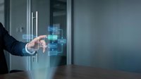 Businessman in dark suit interacting with floating digital interface displaying stacked blue data blocks and network connections in modern office environment for technology and innovation concepts.