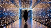 Person walking through illuminated tunnel with thousands of sparkling lights creating magical atmosphere for events, celebrations, and festive displays.