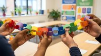 Young child with dark skin tone and adult hands holding colorful stacked blocks in educational classroom setting, demonstrating early learning development and motor skill activities.