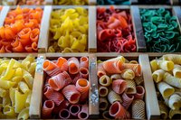 Colorful variety of raw pasta shapes in wooden compartments, perfect for food packaging, restaurant menus, or culinary blog designs. Close-up view showcases traditional Italian cuisine ingredients.
